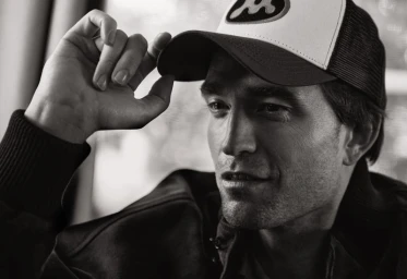 Portrait of Robert Pattinson wearing a trucker hat and jacket for V Magazine Screen Stories by photographer Cass Bird.