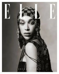 Portrait of a woman wearing a metallic chainmail headpiece and matching dress against a neutral studio backdrop for Elle Brasil