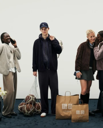 Diverse group of young adults showcase casual apparel with shopping bags against a minimalist backdrop in a fashion editorial.