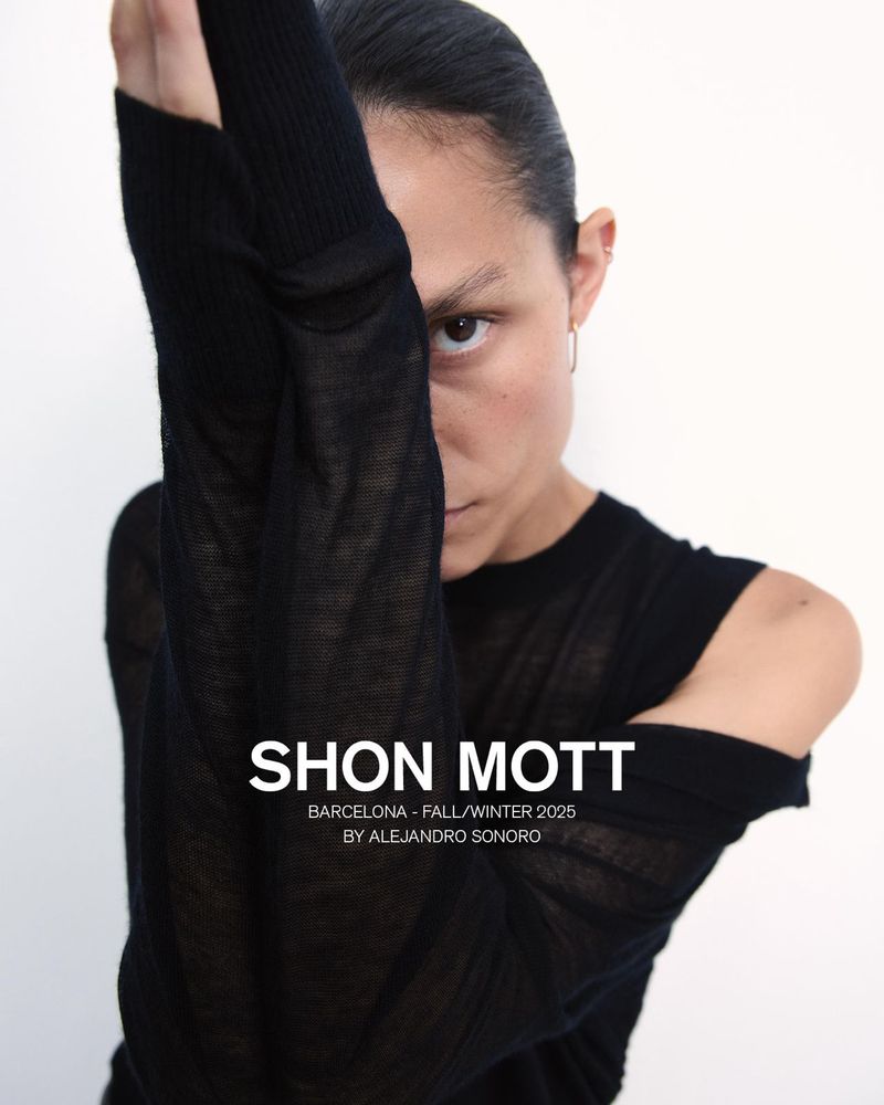 Model wearing a black knit top with raised arms against a white background, photographed by Alejandro Sonoro for Shon Mott.