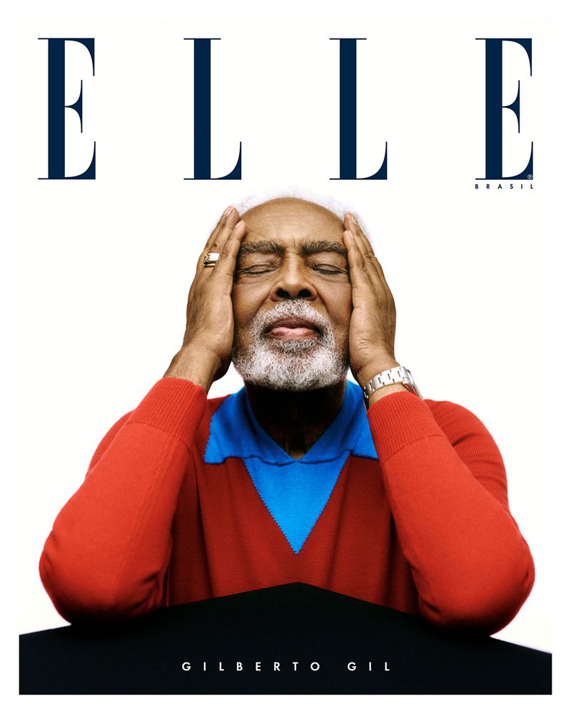 Elderly African-American male on magazine cover. Portrait of person with white hair, wearing a red and blue sweater, against white.