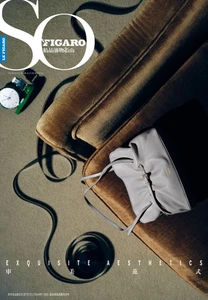 Grey leather handbag and a wristwatch arranged on a brown velvet armchair beside an unspooled film strip.