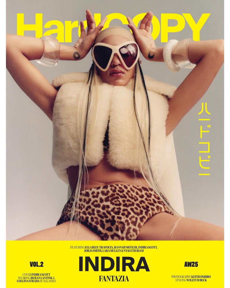 Magazine cover featuring a fair-skinned adult female wearing heart sunglasses, leopard print bottoms, and a fur vest, posing with her hands up.