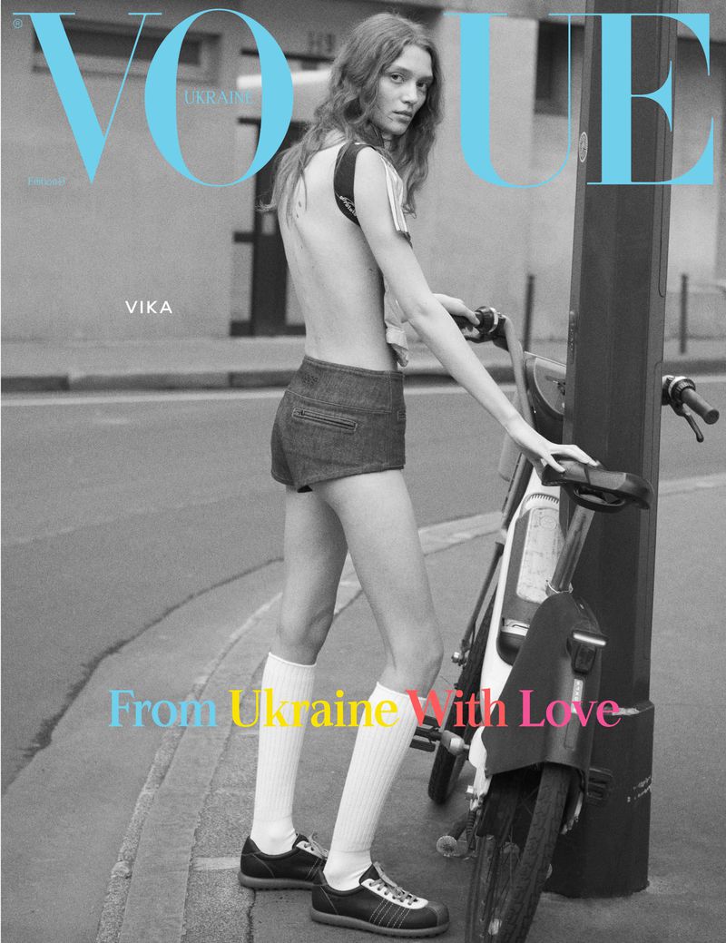 Vogue Ukraine magazine cover featuring a slender model wearing denim shorts, white socks, and sneakers, posing with a rental bike.