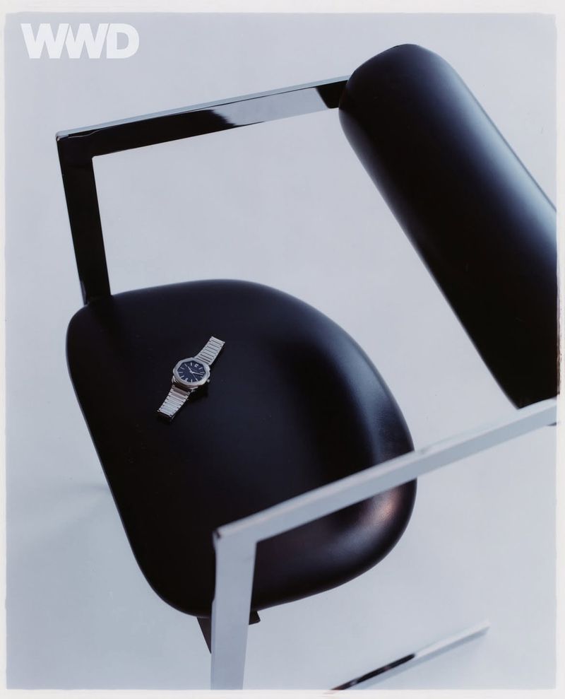 Wristwatch on a modern black chair with chrome frame in a studio setting, emphasizing minimalist design and fashion accessory.