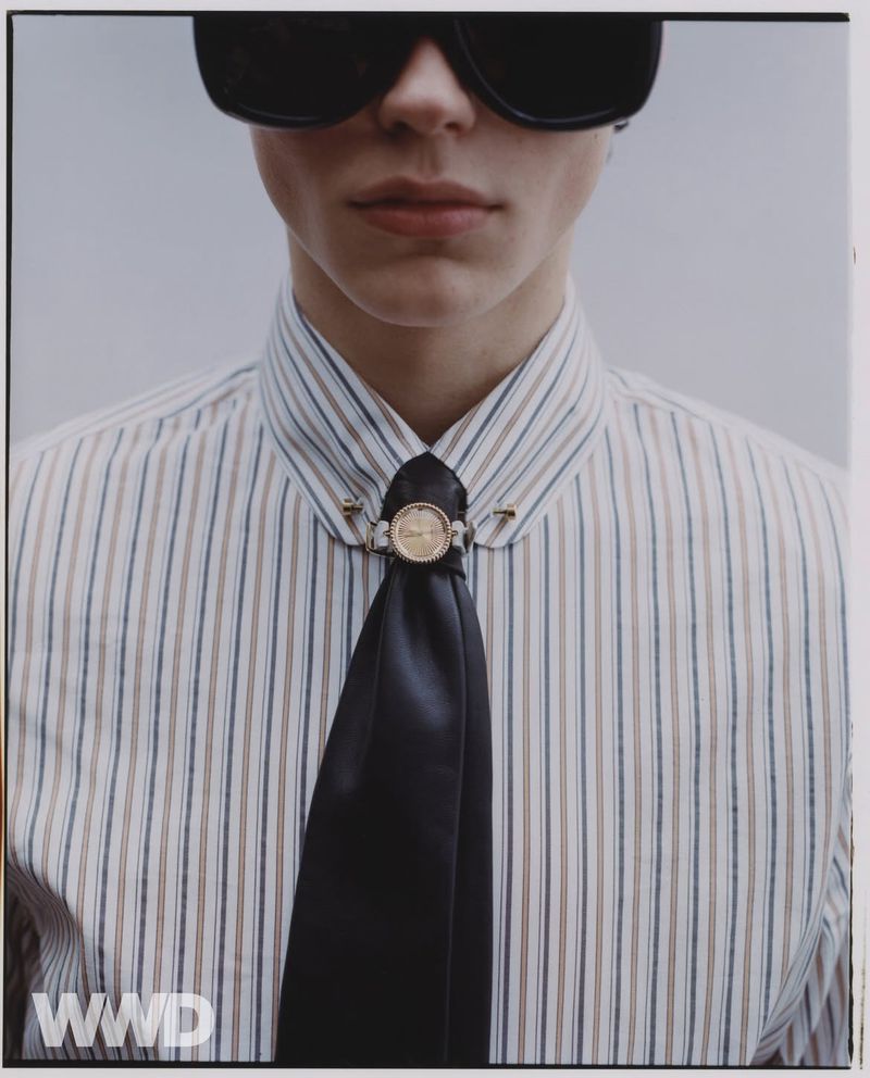 Close-up of a person wearing sunglasses, a striped shirt, and a black tie, creating a stylish and fashionable portrait.