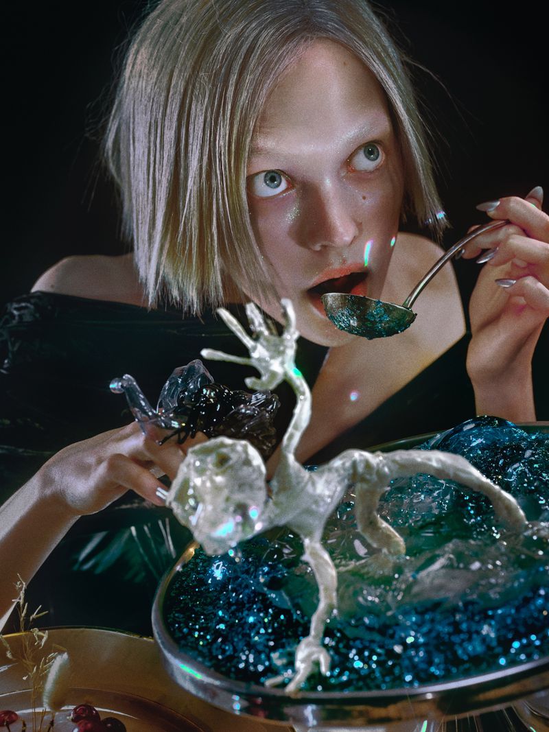 Woman with fair hair eats from a decorated bowl with silver ladle. The composition features an ornate dessert with blue accents.