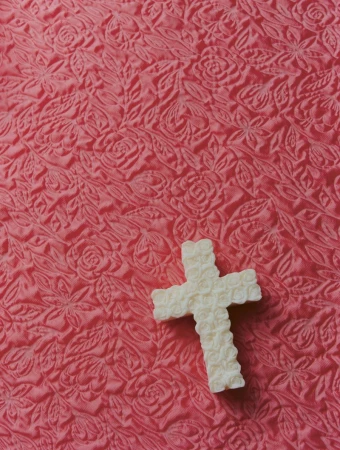 A white cross-shaped textured soap rests on a patterned pink fabric surface for Lampoon Magazine.