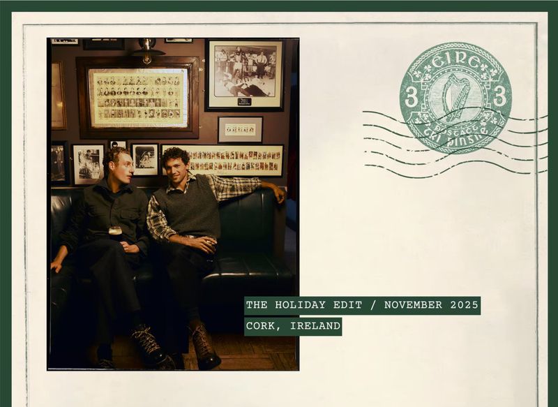 Two adult males seated in an Irish pub with dark wood panelling and framed pictures, captured as a postcard with a postage stamp.