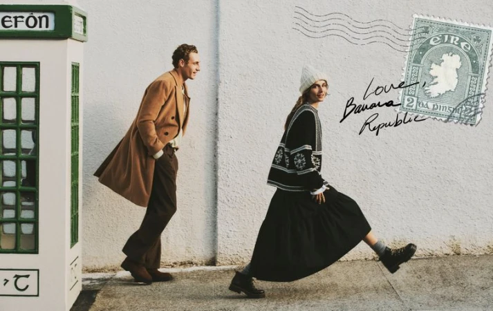 A fashionable man and woman stroll past a green phone booth, creating a vintage aesthetic for a Banana Republic advertisement.