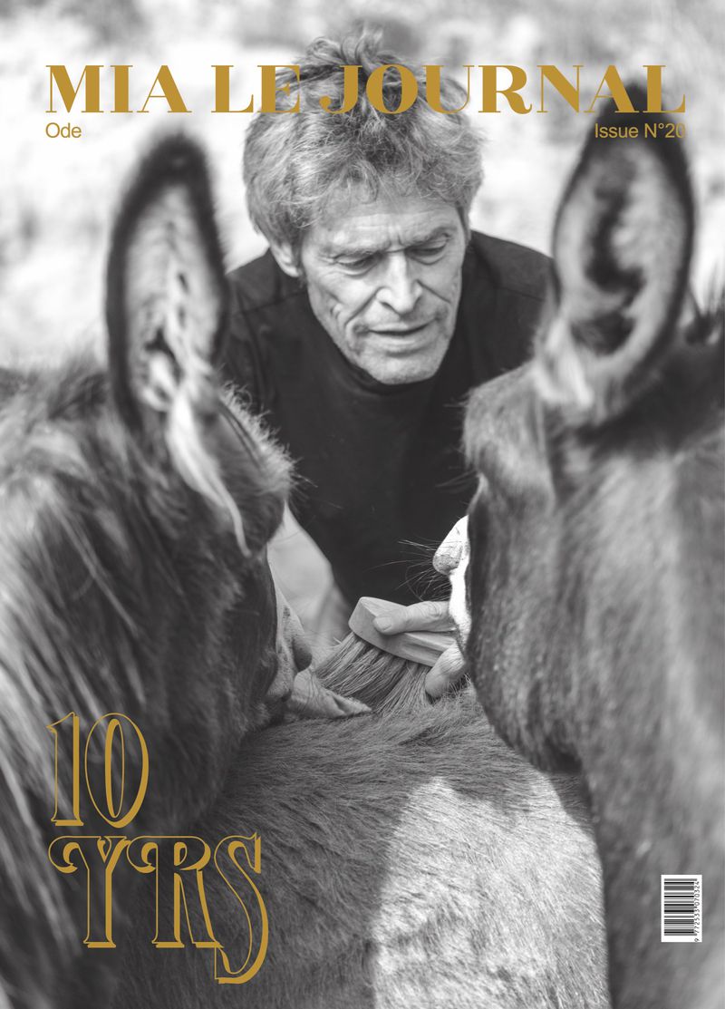 Magazine cover featuring Willem Dafoe with donkeys, grayscale image with gold text accents for 'Mia Le Journal' and '10 YRS'.
