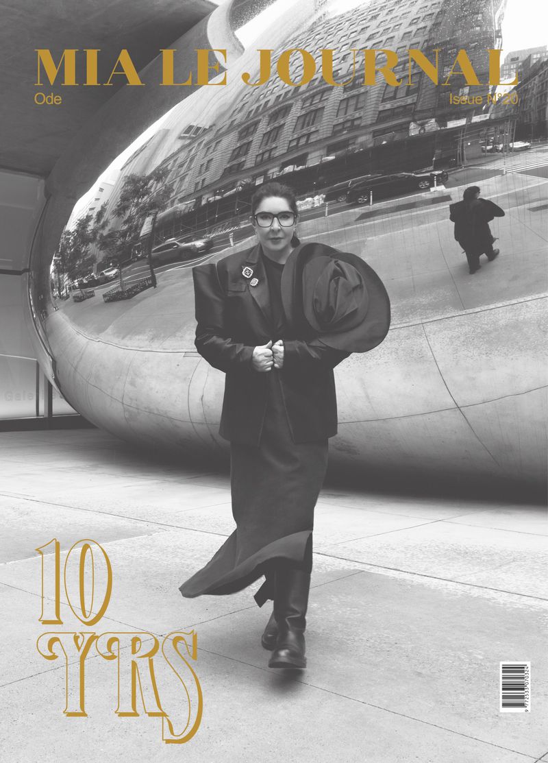 Magazine cover featuring a woman in a black suit standing in front of a reflective sculpture with a building visible in the reflection.