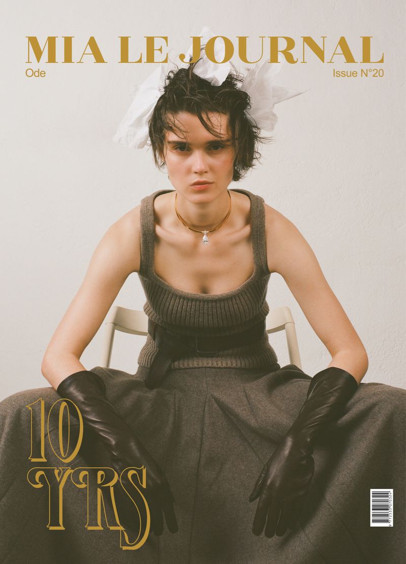 Model wearing a knit tank top, leather gloves, and headpiece seated against a plain background for Mia Le Journal