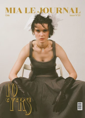 Model wearing a knit tank top, leather gloves, and headpiece seated against a plain background for Mia Le Journal