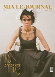 Model wearing a knit tank top, leather gloves, and headpiece seated against a plain background for Mia Le Journal