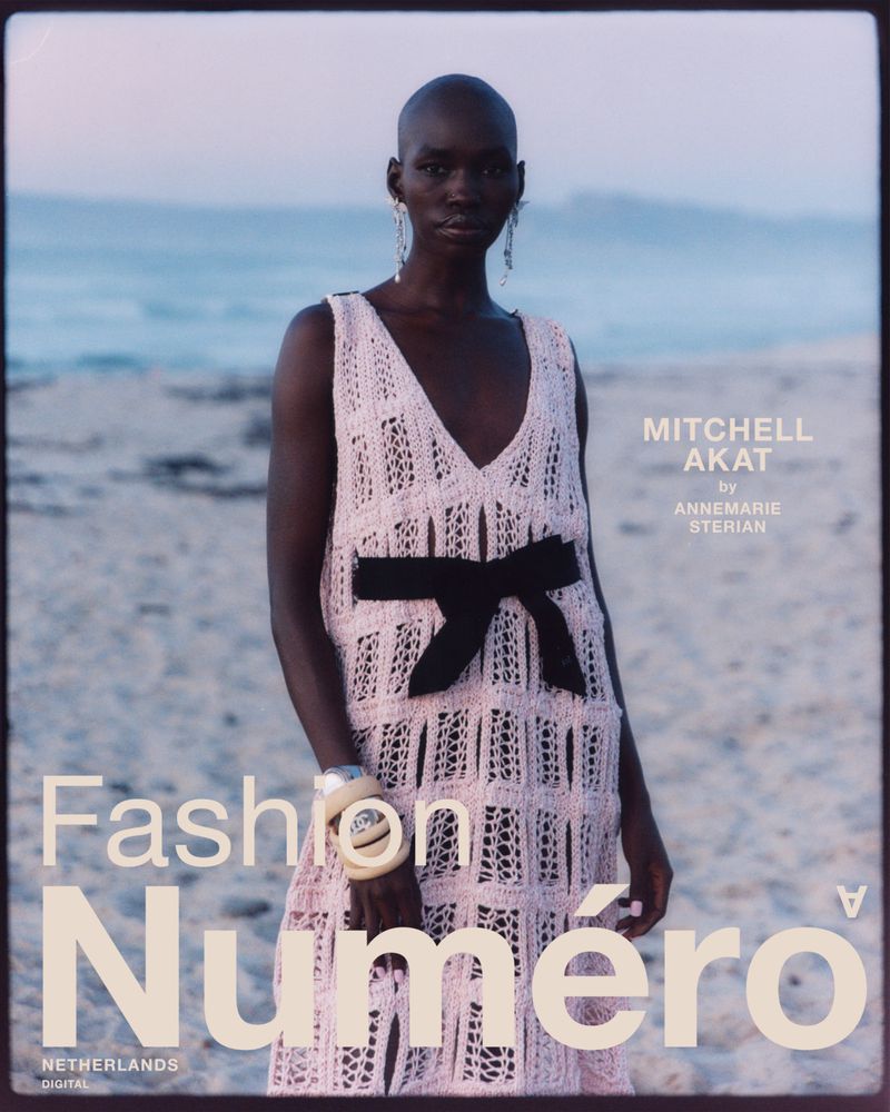 Fashion magazine cover featuring a woman in a pink knit dress on a beach with the ocean and sky as a backdrop at dusk.