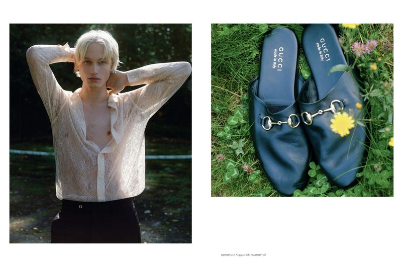Fashion editorial featuring a young adult with blond hair wearing an open lace shirt in a grassy outdoor setting, with Gucci loafers.