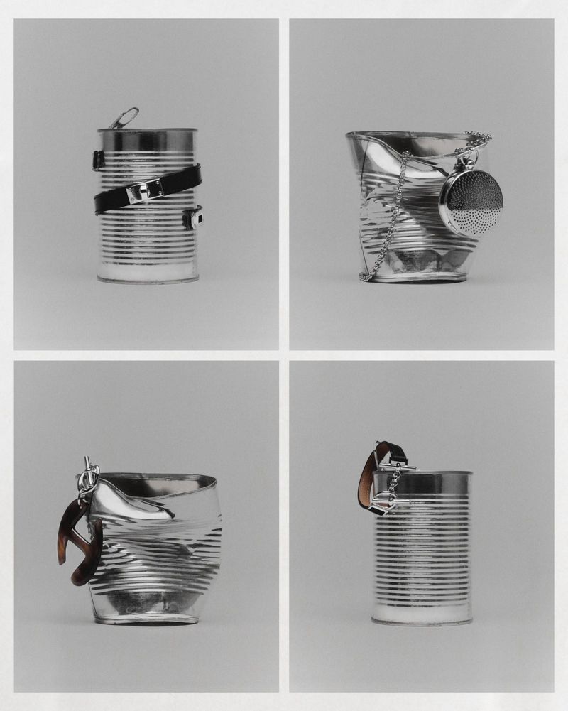Conceptual still life featuring tin cans repurposed with belts, chain, and watch accessories, arranged in a neat square grid on a grey backdrop.