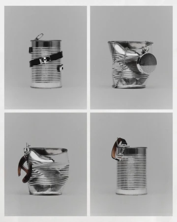 Conceptual still life featuring tin cans repurposed with belts, chain, and watch accessories, arranged in a neat square grid on a grey backdrop.