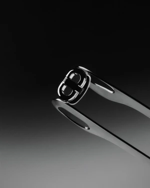 Macro photograph of polished silver metallic designer hardware against a dark gradient studio background.