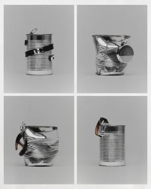 Four-panel grid of black and white still life photographs featuring metallic tin cans styled with luxury jewellery and leather accessories.