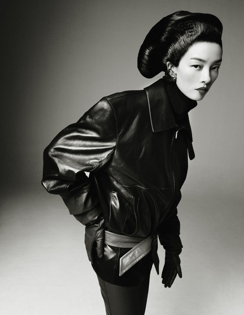 FeiFei Sun wears an oversized black leather jacket with a sculptural updo hairstyle in a high-contrast black and white fashion portrait.