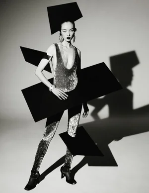 Model Fei Fei Sun poses in a shimmering bodysuit surrounded by floating black geometric rectangles in black and white.
