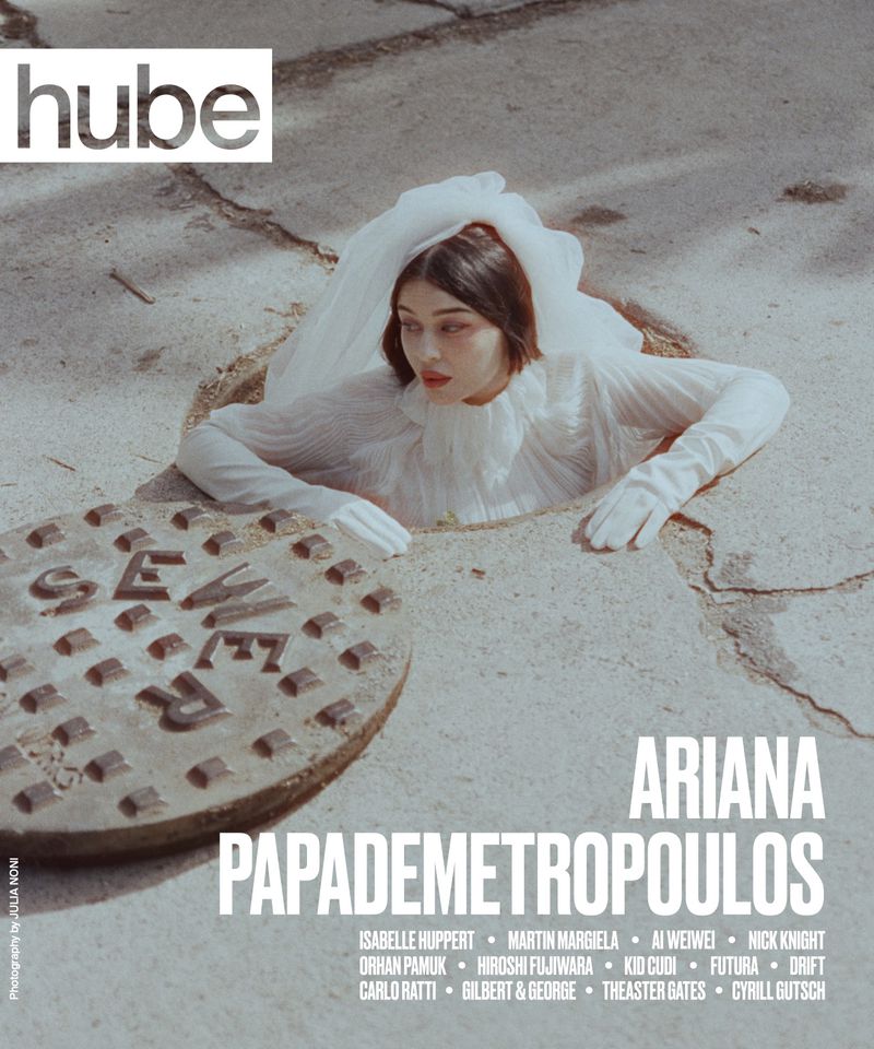 Magazine cover featuring a woman in a white dress and gloves emerging from a manhole, with the magazine title 'hube' displayed.