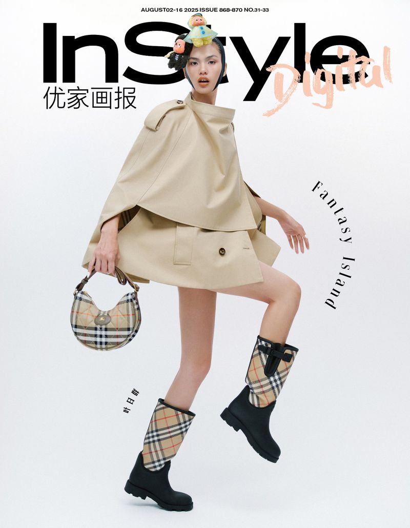 Editorial fashion shot of an Asian woman in a beige cape dress, Burberry boots and handbag, against a white background for InStyle.
