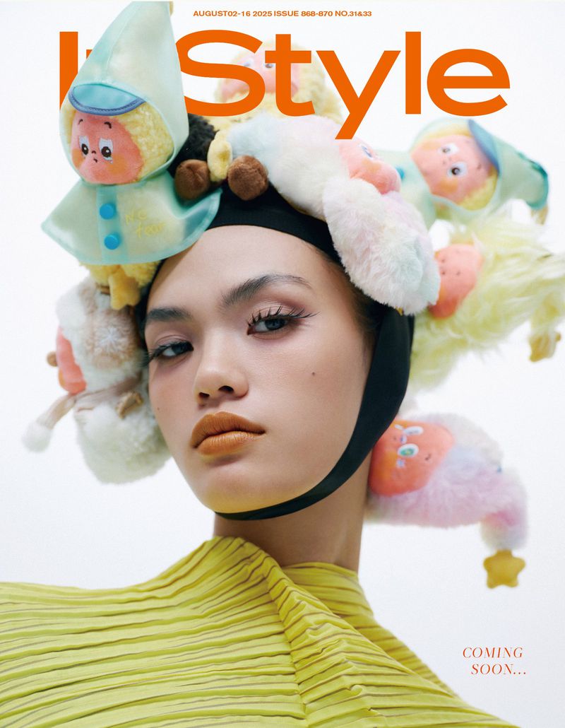 Fashion magazine cover featuring an Asian woman with avant-garde style, adorned with plush toys in a light, airy photo studio setting.