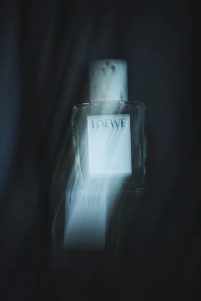 Loewe perfume bottle captured with vertical motion blur and streak effects against a dark minimal background.