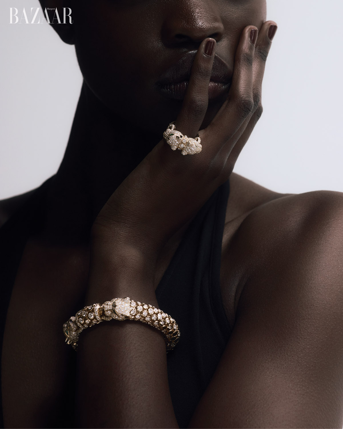 Close-up shot of an African American female model wearing a black top and jewelry featuring sparkling rings and a snake bracelet.