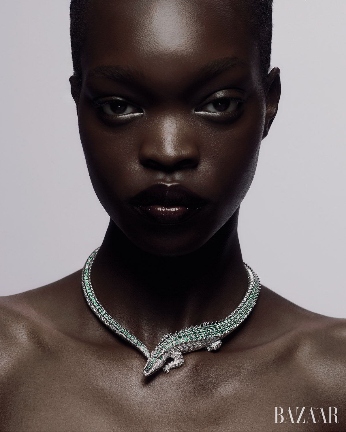 Headshot of a black woman with a short haircut and an alligator diamond necklace against a grey background. Fashion, beauty concept.