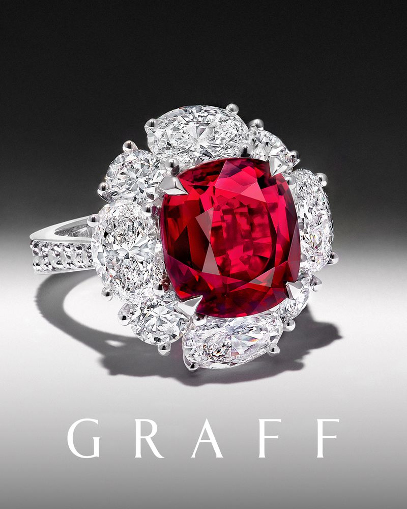 Close-up of a GRAFF ring featuring a large, cushion-cut ruby surrounded by white diamonds, set against a soft gradient background.