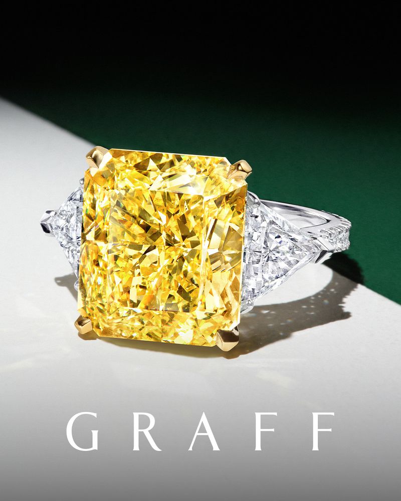 Close-up of a yellow diamond ring, featuring a large radiant-cut yellow diamond center stone with trapezoid-shaped white diamonds.