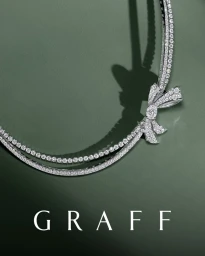 Graff diamond bow necklace casting a distinct shadow against a muted green studio background with white brand logo.
