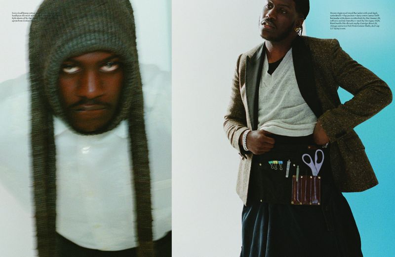 Editorial fashion shot featuring an African American male model in a grey knit beanie and a brown tweed blazer against a white and blue backdrop.