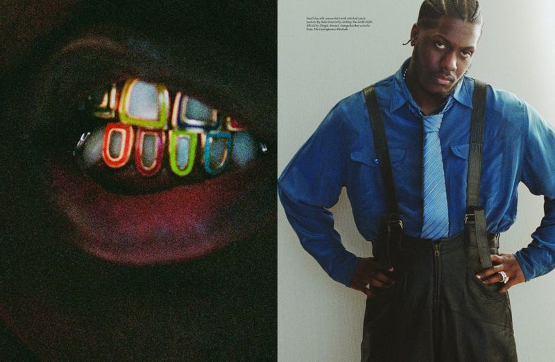 Close-up of colorful grill on teeth, juxtaposed with a stylish man in a blue shirt, tie, and leather pants against a white wall.