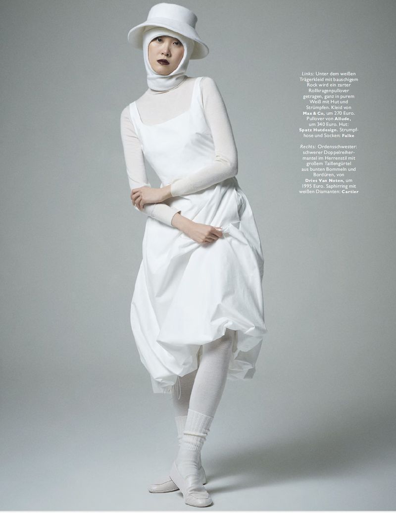 A fashion shot features an Asian woman in an all-white ensemble, including a dress, hat, and tights, standing in a light grey studio setting.