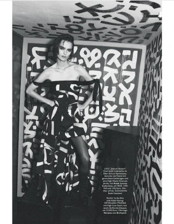 Fashion editorial shot of a model in a black-and-white dress, standing in a room with graffiti art, creating a bold and artistic composition.