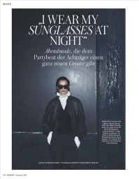 Model Beck Hume wearing dark sunglasses, a black leather jacket, and waistcoat against a dark door in a fashion editorial for Madame Germany.