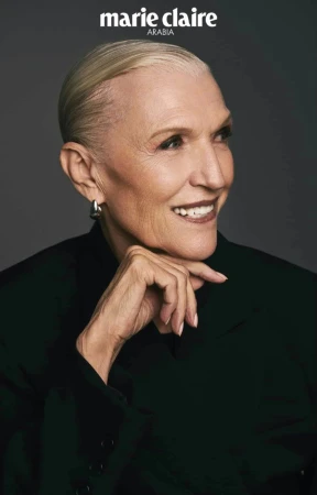 Portrait of Maye Musk with slicked-back blonde hair wearing a black jacket against a dark grey background for Marie Claire Arabia