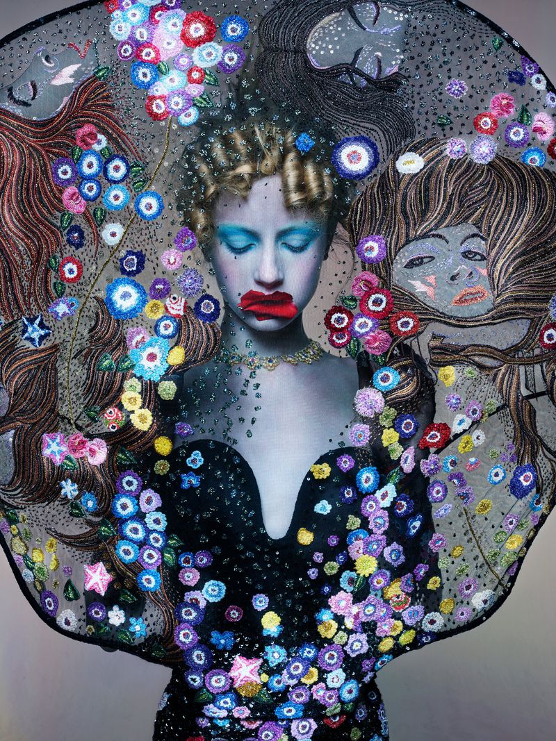 Artistic fashion portrait of a woman in a floral dress and veil, with illustrated faces in the background. Eye-level angle, studio shot.