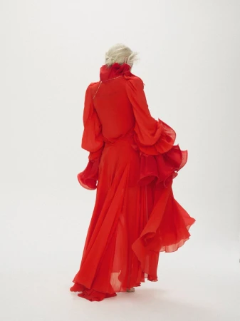 Model wearing a vibrant red ruffled chiffon dress shot from behind against a plain white background.