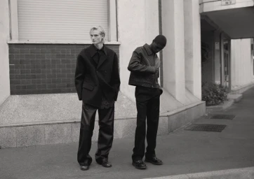 Two male models posing on a city street in dark structured jackets and trousers for Arena Homme Plus China.