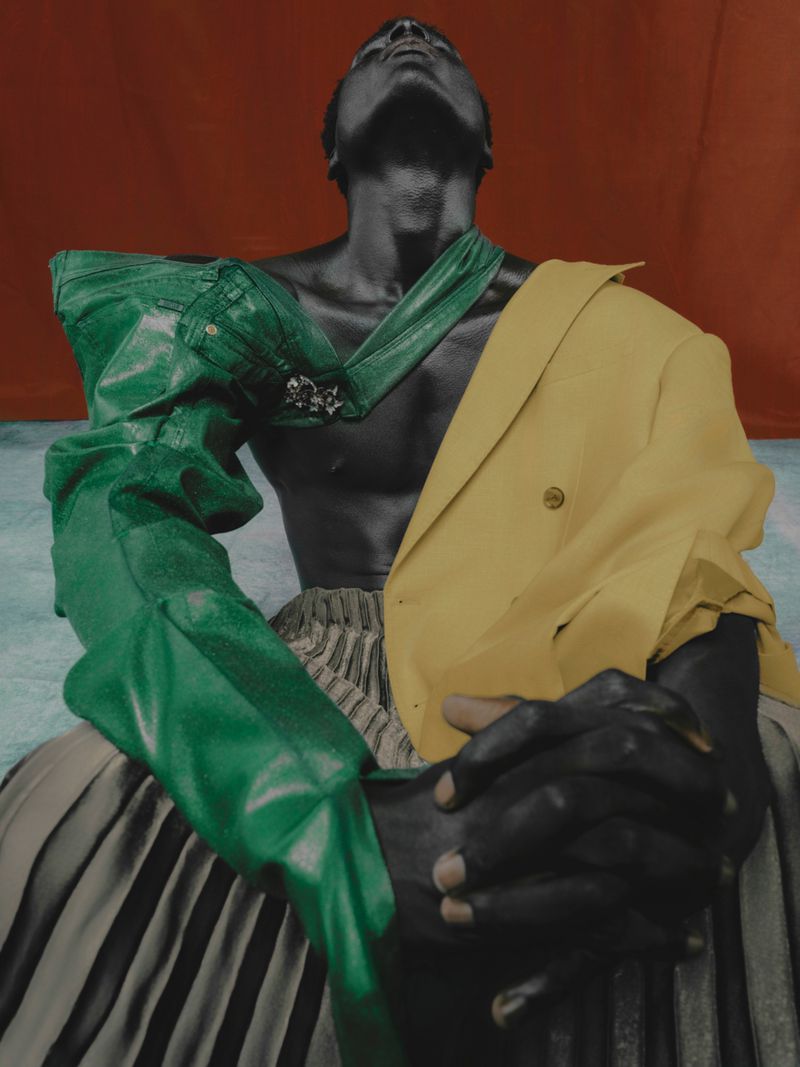 Artistic studio portrait of an adult male wearing a green top and yellow jacket, set against a red and blue background.