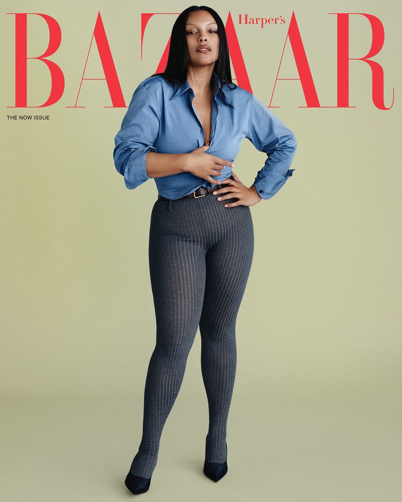 Model Paloma Elsesser in a blue button-down shirt and grey leggings against a solid backdrop for Harper's Bazaar US.