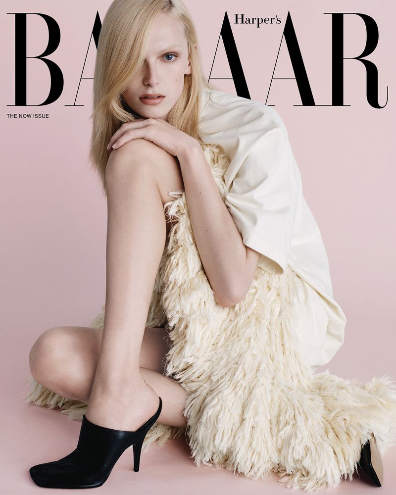 Magazine cover featuring a fair-skinned adult female model in a light-colored shirt and black high-heeled mules, sitting against a pink backdrop.