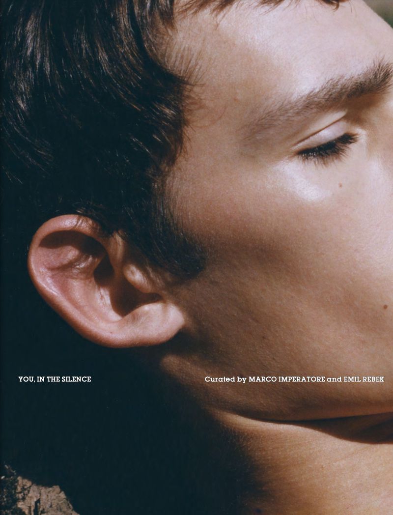 Close-up portrait of a young fair-skinned man with his eyes closed, featuring soft, natural lighting and a dark background.