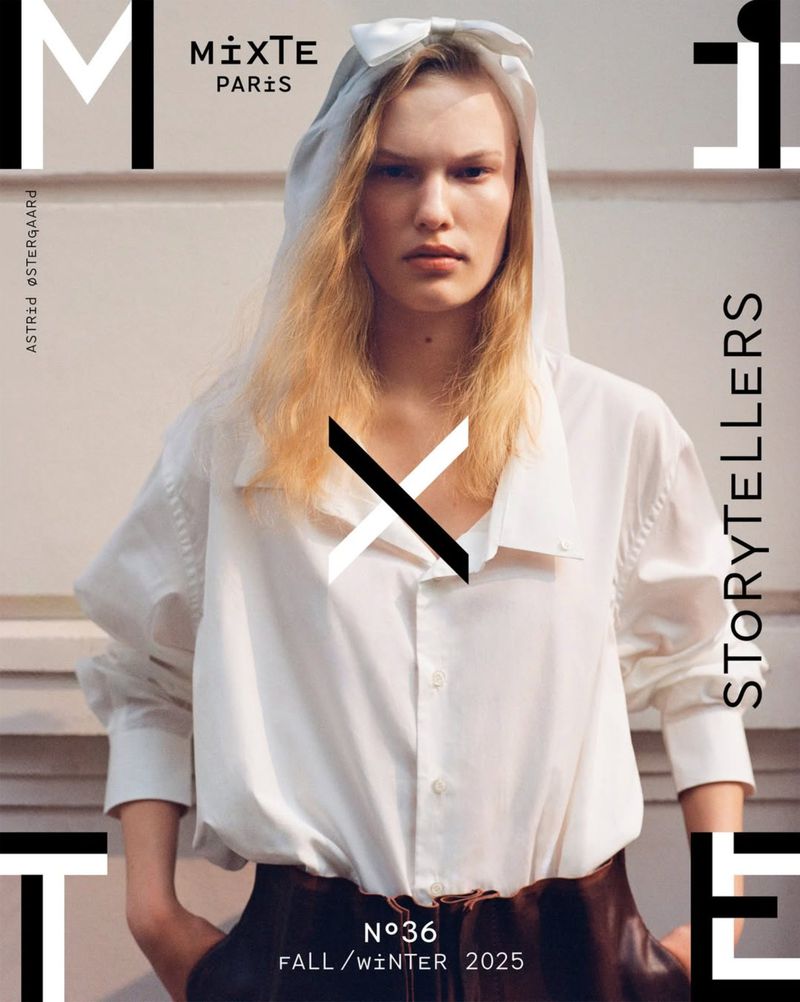 Editorial fashion shot: A woman with fair skin, wearing a white hooded garment and shirt, poses against a white backdrop with magazine graphics.